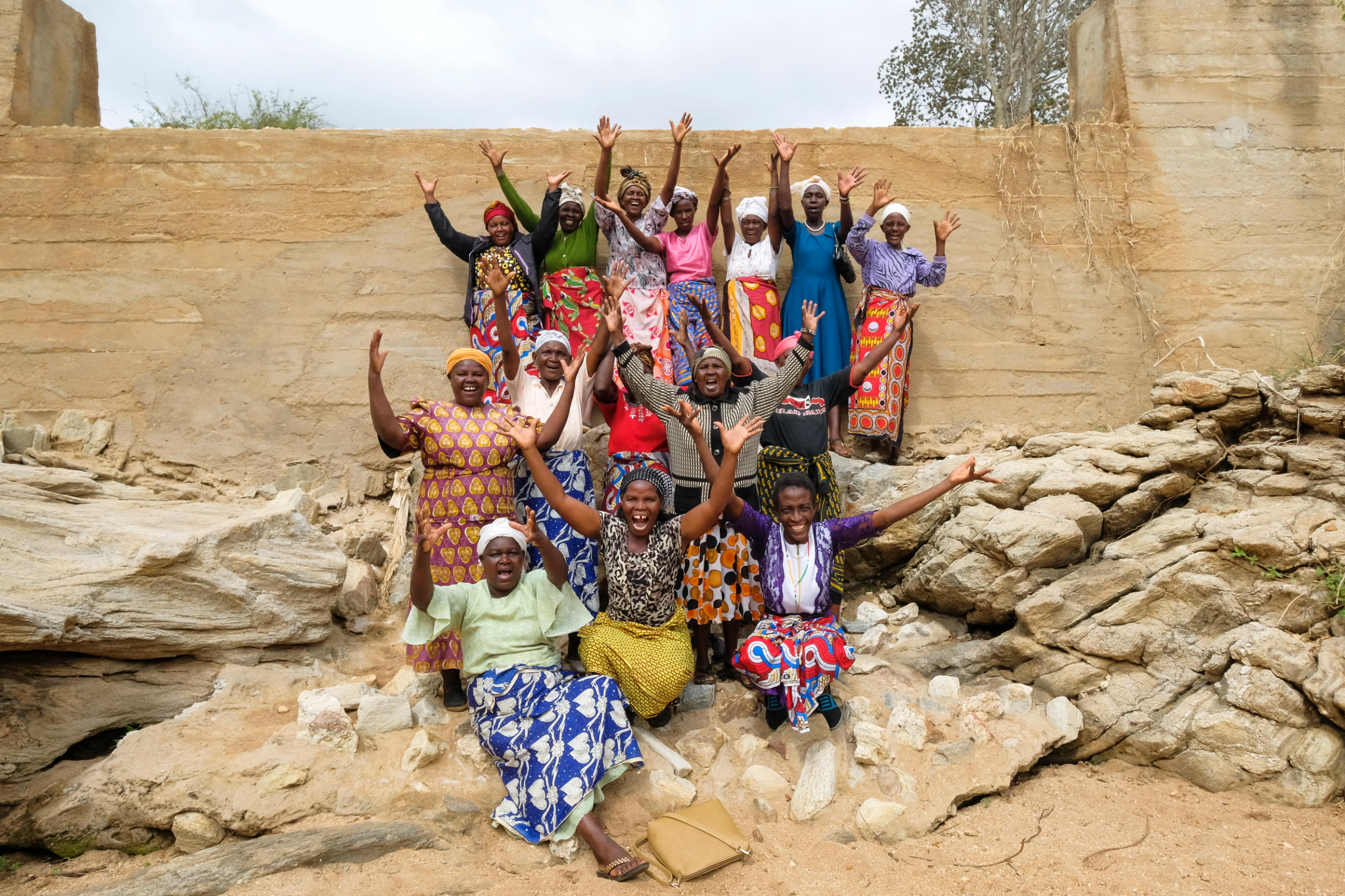 Eine Gruppe Frauen mit erhobenen Händen vor einer Steinmauer