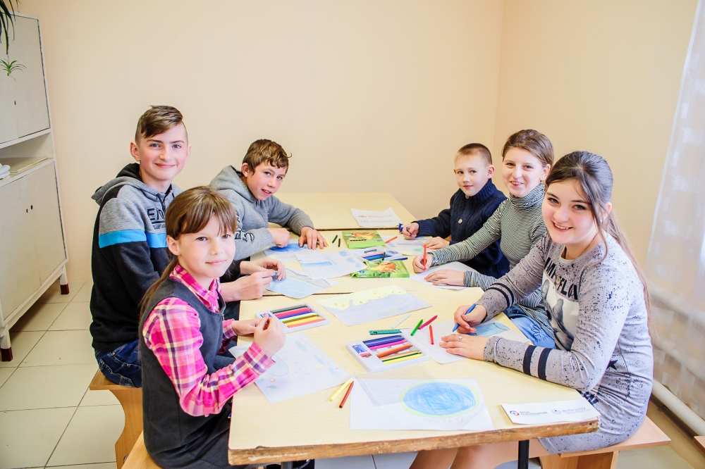 Kinder sitzen an Tisch und malen