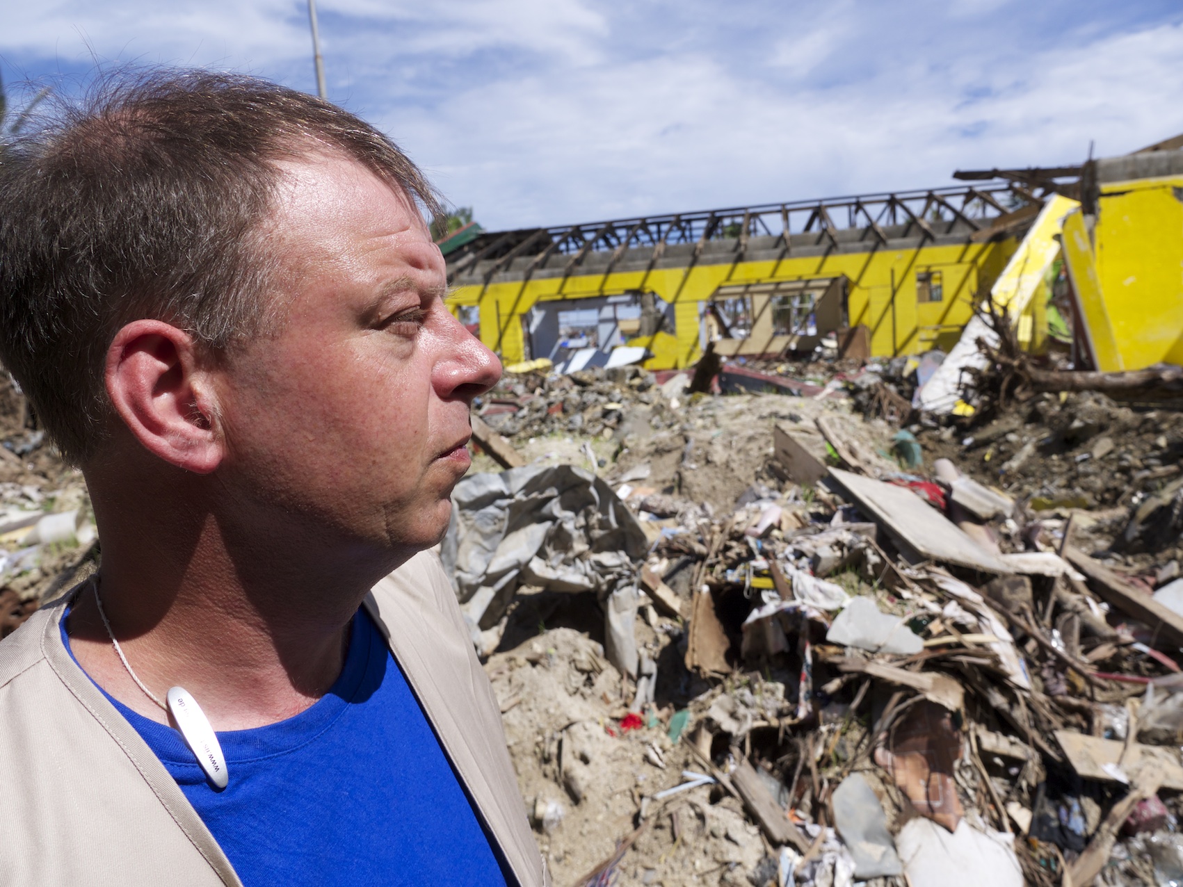 Friedrich Machein im Profil im Vordergrund. Im Hintergrund eine Trümmerlandschaft.