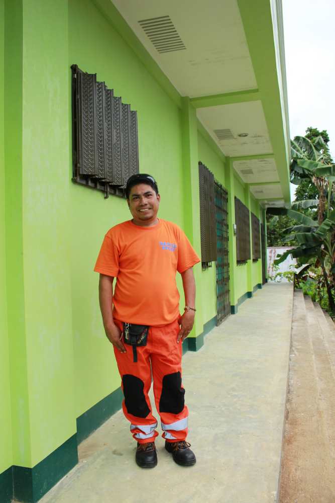 Mann mit orangener Kleidung vor grünem Haus